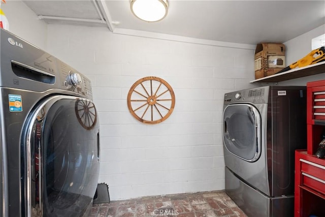 washroom with laundry area, brick floor, and washer and clothes dryer