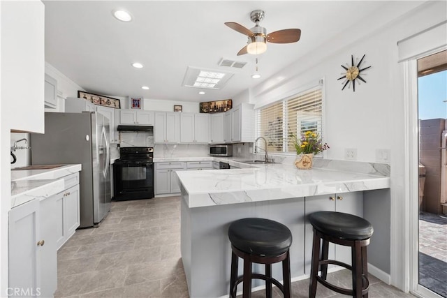 27071 Calle Caballero Unit B, San Juan Capistrano, CA 92675 - kitchen featuring appliances with stainless steel finishes, under cabinet range hood, a peninsula, a ceiling fan, and a kitchen bar