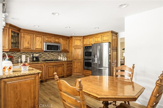 9492 Brynmar Dr, Villa Park, CA 92861 - kitchen featuring stainless steel appliances, brown cabinetry, light wood finished floors, tasteful backsplash, and light stone counters