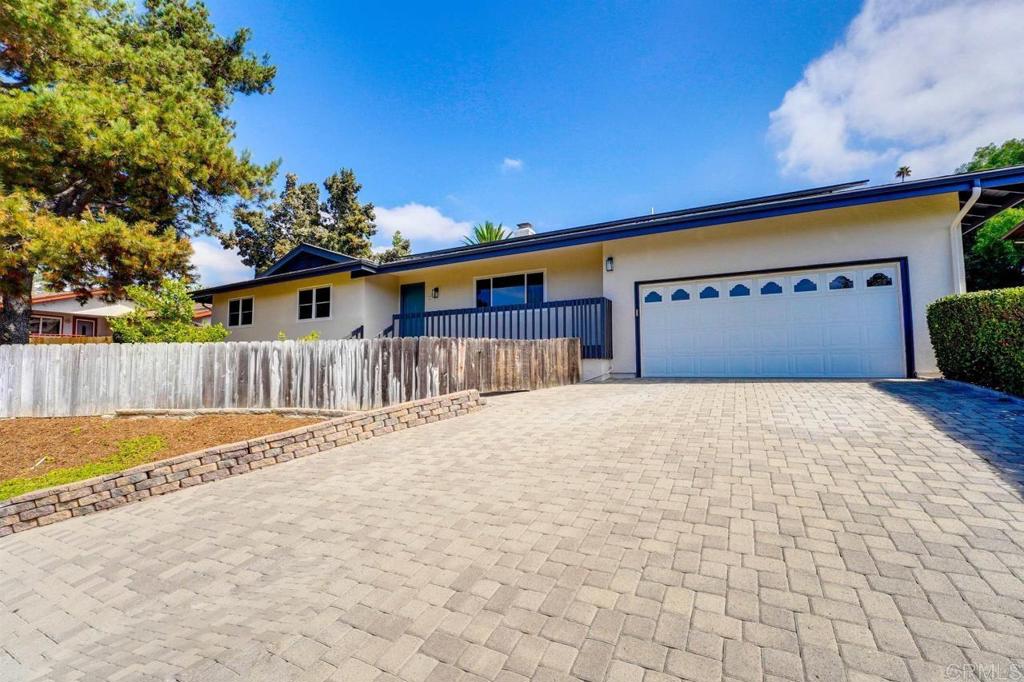 ranch-style home featuring stucco siding, a garage, fence, and decorative driveway