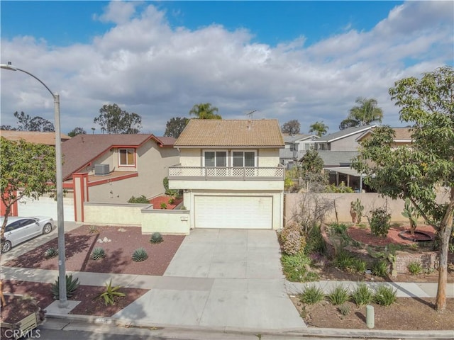 traditional-style home featuring an attached garage, a tiled roof, stucco siding, fence, and driveway