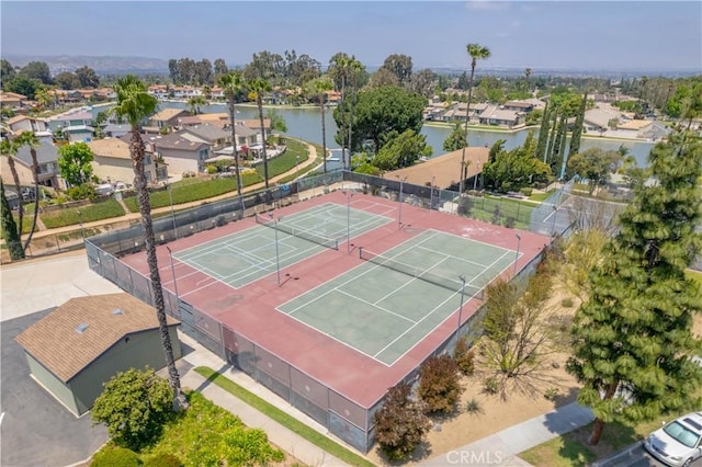 view of sport court featuring a water view, a residential view, and fence