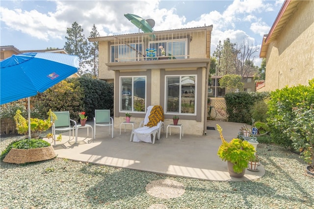 rear view of property with a patio, stucco siding, and a balcony