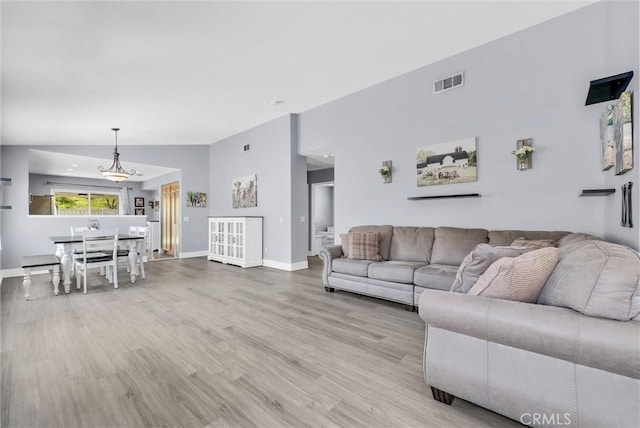 living room featuring baseboards, visible vents, and wood finished floors
