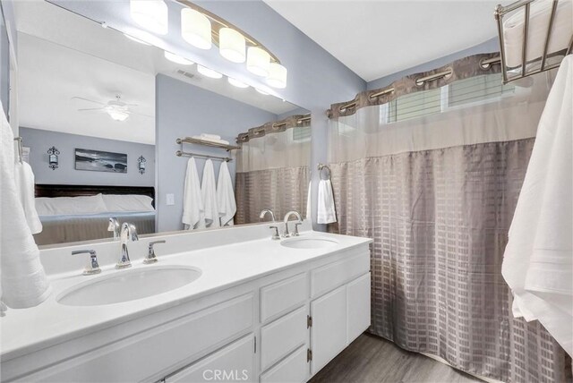full bathroom with ceiling fan, ensuite bath, double vanity, and a sink
