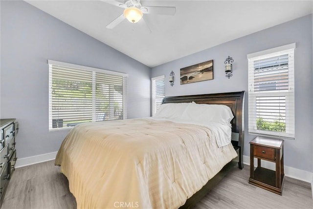 bedroom featuring light wood finished floors, multiple windows, vaulted ceiling, and baseboards