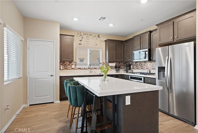 26643 Baneberry Ct, Menifee, CA 92585 - kitchen with stainless steel appliances, dark brown cabinets, tasteful backsplash, a breakfast bar area, and a sink