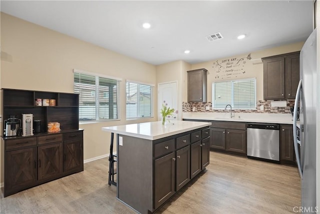 26643 Baneberry Ct, Menifee, CA 92585 - kitchen with appliances with stainless steel finishes, a sink, light wood-type flooring, a breakfast bar area, and decorative backsplash