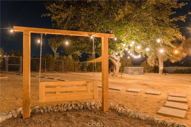 yard at twilight featuring a hot tub and fence