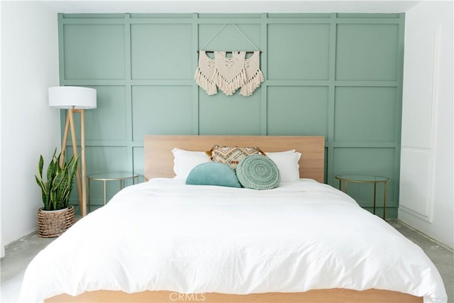 bedroom with a decorative wall and concrete flooring