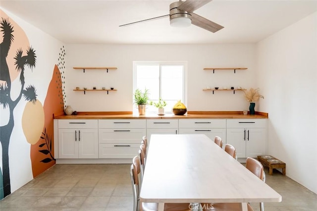 kitchen featuring open shelves, a ceiling fan, white cabinets, and wood counters