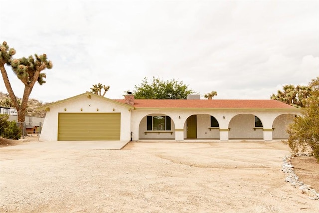 single story home with driveway, an attached garage, stucco siding, and a chimney