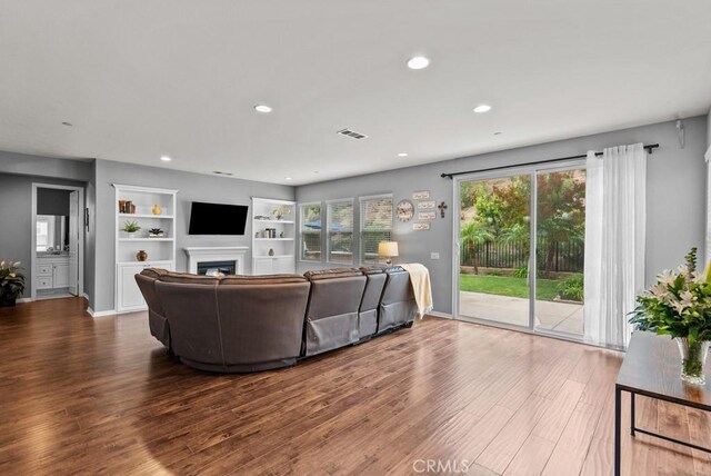19321 Carranza Ln, Saugus, CA 91350 - living area featuring wood finished floors, a fireplace, visible vents, built in shelves, and recessed lighting