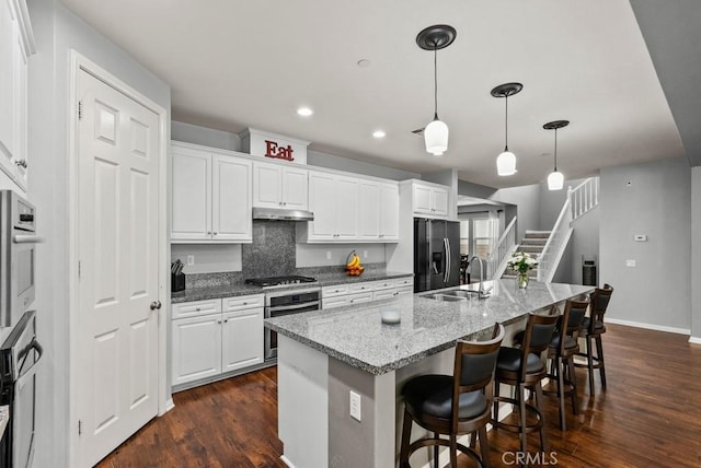 19321 Carranza Ln, Saugus, CA 91350 - kitchen featuring a sink, dark wood finished floors, under cabinet range hood, white cabinets, and appliances with stainless steel finishes
