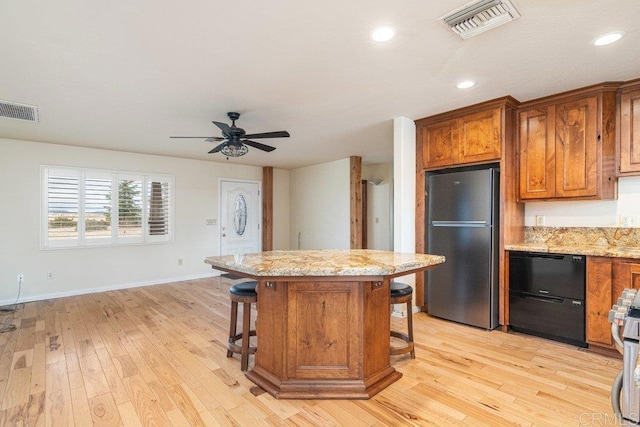 kitchen featuring freestanding refrigerator, visible vents, brown cabinets, and baseboards