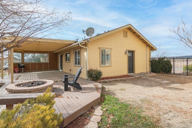 back of house featuring a pergola, an outdoor fire pit, a wooden deck, and fence