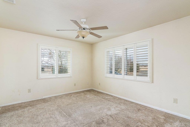 empty room featuring a ceiling fan, baseboards, visible vents, and carpet floors