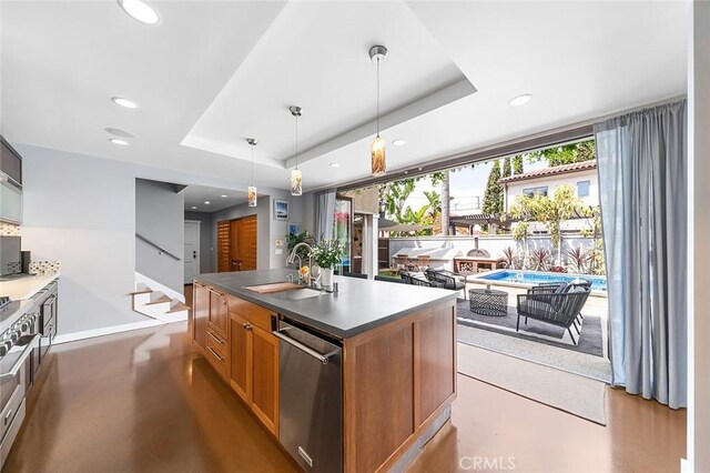 291 Argonne Ave, Long Beach, CA 90803 - kitchen featuring stainless steel appliances, a tray ceiling, dark countertops, an island with sink, and brown cabinets