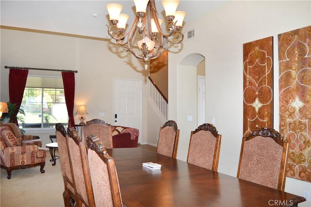 13622 Canyon Crest Rd, Yucaipa, CA 92399 - dining space featuring arched walkways, a chandelier, stairs, a towering ceiling, and carpet floors