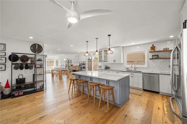 19542 Constellation Ln, Huntington Beach, CA 92646 - kitchen featuring a sink, stainless steel appliances, a breakfast bar, light wood-style flooring, and white cabinetry