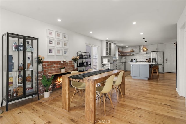 19542 Constellation Ln, Huntington Beach, CA 92646 - dining room with light wood-style floors, recessed lighting, and a brick fireplace