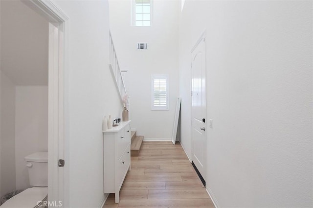 7343 Anise Ln, Chino, CA 91708 - hallway featuring healthy amount of natural light, light wood-style flooring, baseboards, and a towering ceiling
