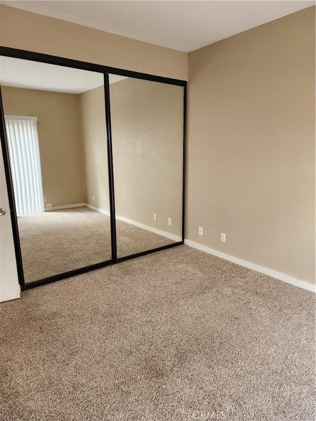unfurnished bedroom with carpet flooring, baseboards, and a closet