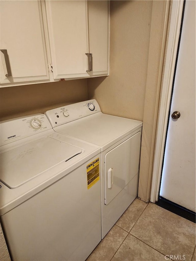 washroom with cabinet space, washing machine and clothes dryer, and light tile patterned floors
