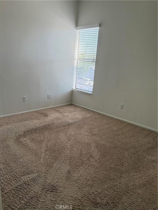 carpeted empty room featuring baseboards