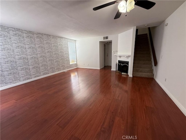 20821 E Calora St Unit E1, Covina, CA 91724 - unfurnished living room with ceiling fan, baseboards, stairs, wood finished floors, and brick wall