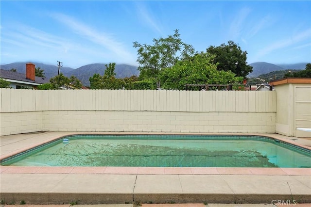 view of swimming pool with a mountain view and a fenced backyard