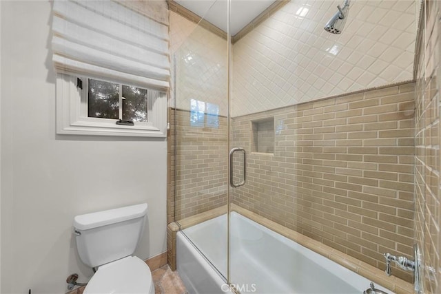 bathroom featuring toilet, enclosed tub / shower combo, and baseboards