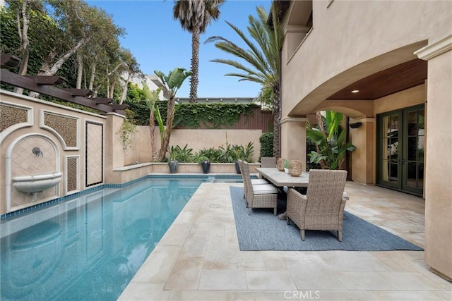 view of pool featuring a patio, fence, outdoor dining area, and french doors