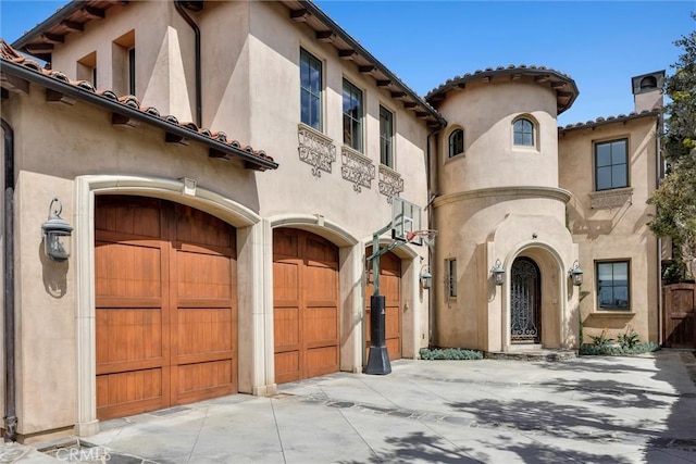 mediterranean / spanish home featuring driveway, a chimney, stucco siding, and an attached garage
