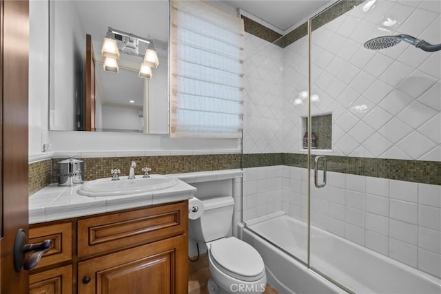 bathroom featuring toilet, shower / bath combination with glass door, and vanity