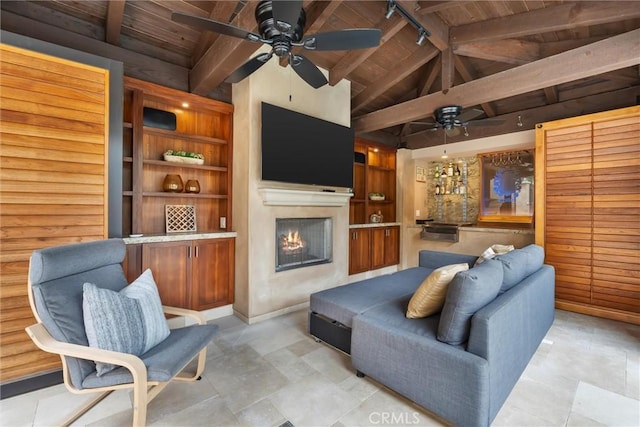 living area featuring wood ceiling, a ceiling fan, a warm lit fireplace, track lighting, and baseboards