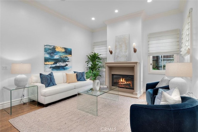 living room featuring crown molding, wood finished floors, a glass covered fireplace, recessed lighting, and baseboards