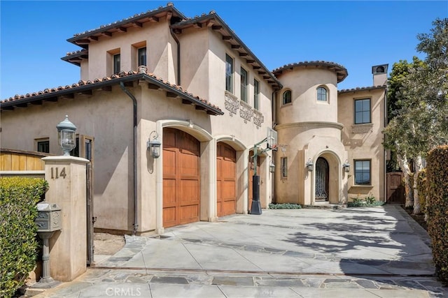 mediterranean / spanish-style house with driveway, fence, stucco siding, and an attached garage