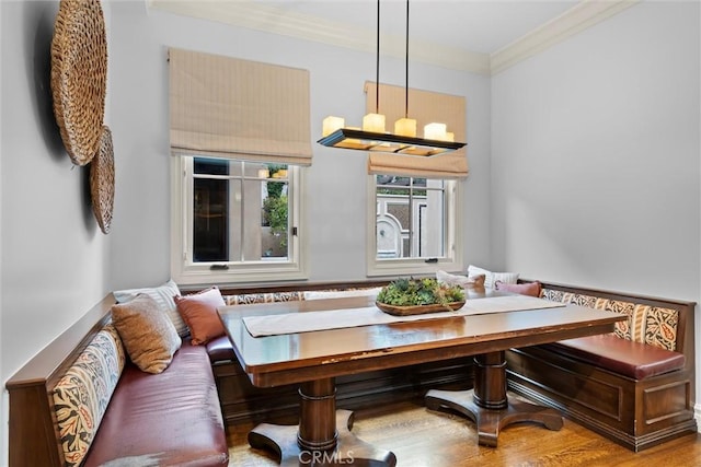 dining room featuring breakfast area, ornamental molding, wood finished floors, and a chandelier