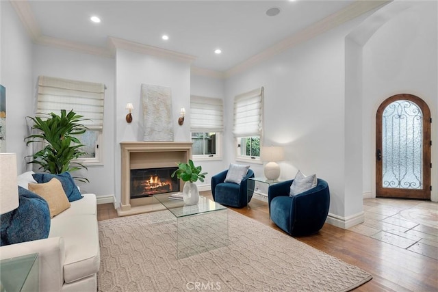 living room with ornamental molding, baseboards, wood finished floors, recessed lighting, and a glass covered fireplace