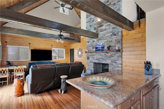 28935 Banff Dr, Lake Arrowhead, CA 92352 - living room featuring a fireplace, hardwood / wood-style floors, wood walls, beamed ceiling, and ceiling fan