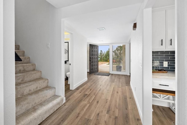 foyer with stairway, light wood finished floors, and baseboards