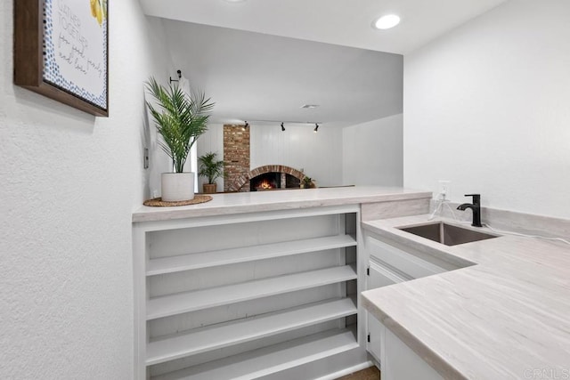 interior space with a brick fireplace, recessed lighting, and a sink