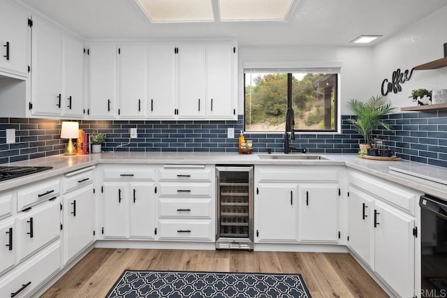 kitchen with white cabinetry, light countertops, beverage cooler, and a sink