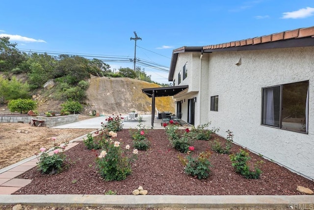 view of side of home with stucco siding and a patio