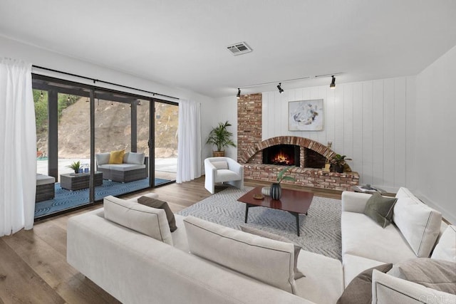 living area with rail lighting, a fireplace, visible vents, and wood finished floors