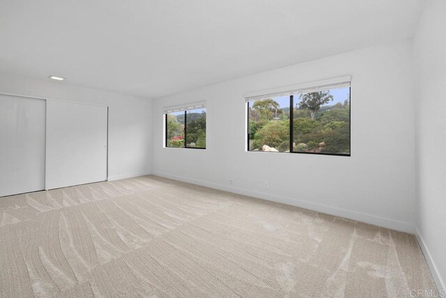 unfurnished room with baseboards and light carpet