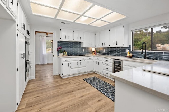 kitchen featuring wine cooler, light countertops, tasteful backsplash, and visible vents