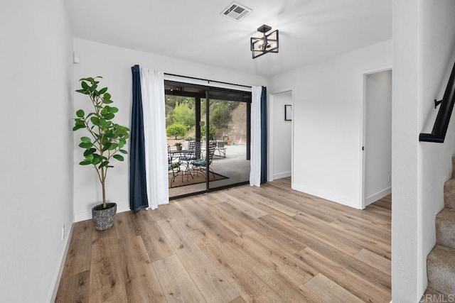 interior space with baseboards, light wood-style flooring, and visible vents