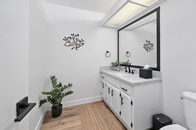 bathroom featuring vanity, toilet, baseboards, and wood finished floors